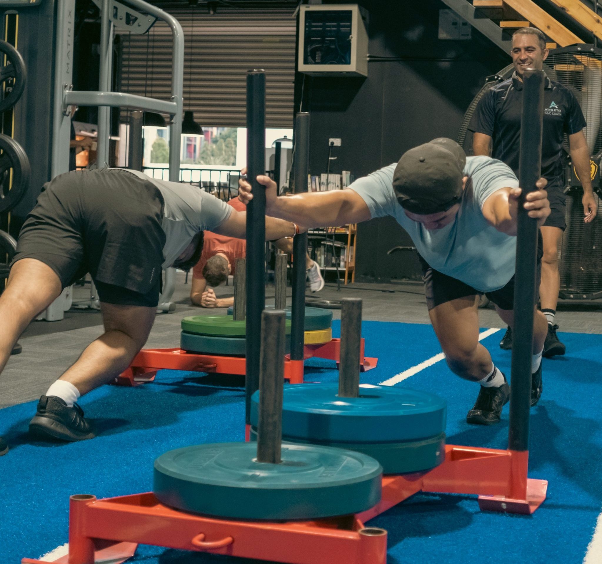 HIIT Push and Drag class at ATHLETIX Brisbane — athlete pushing weighted sled on track